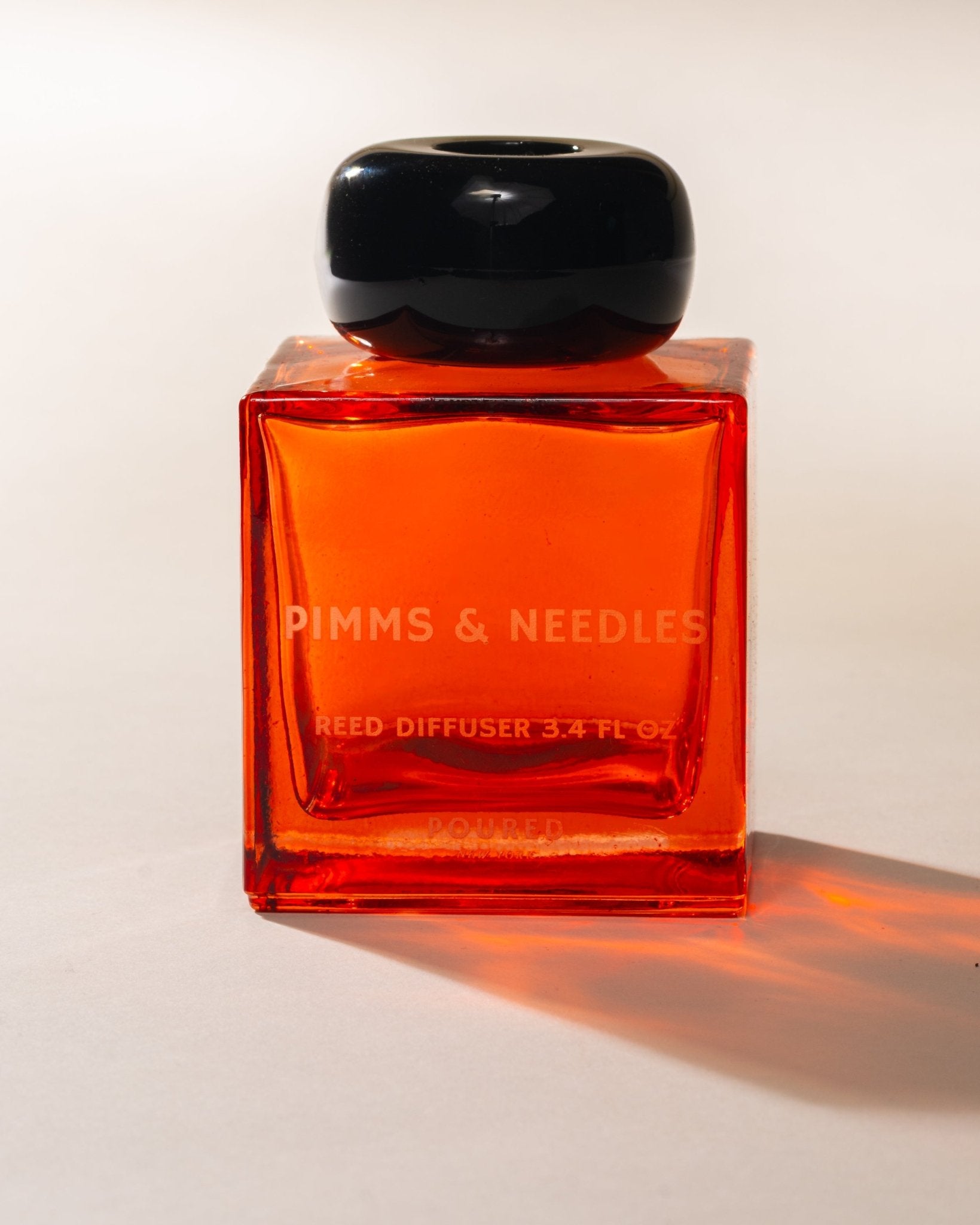 Poured New York 'Pimms & Needles' red square reed diffuser with black circular cap on a neutral background