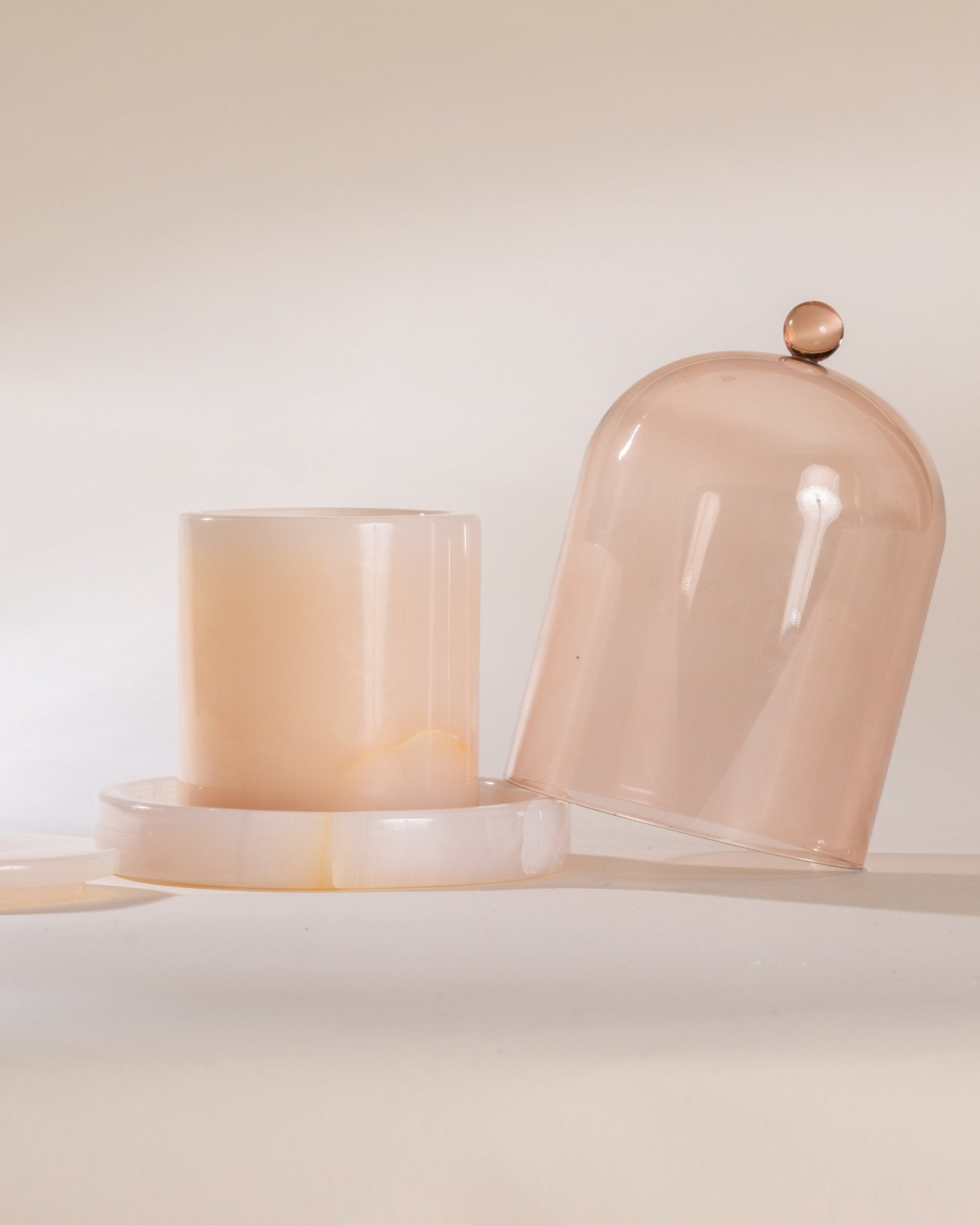 Two peach-colored glass containers with a dome lid on a light background