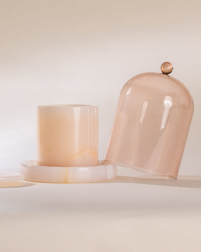 Two peach-colored glass containers with a dome lid on a light background