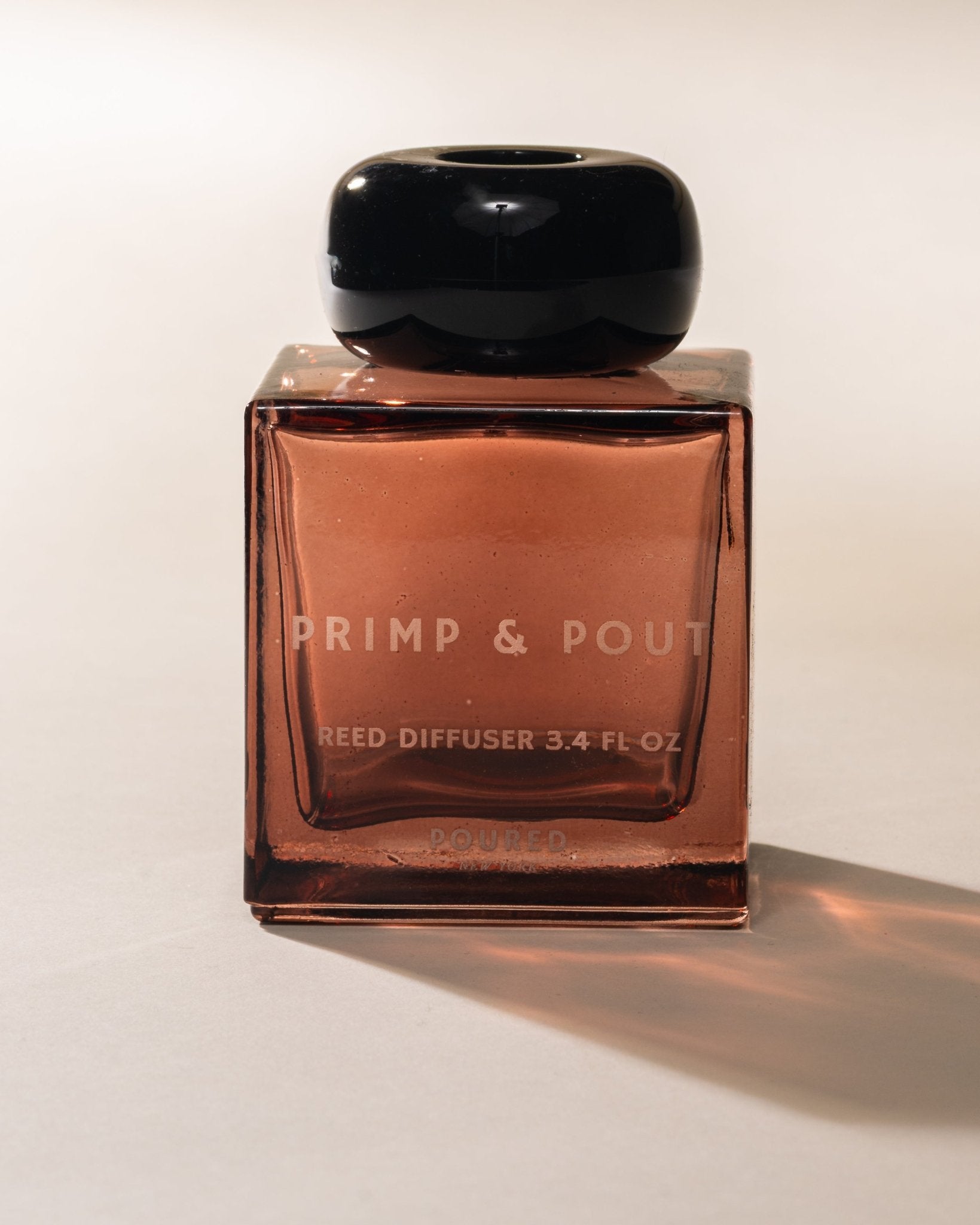 Poured New York 'Primp & Pout' Reed diffuser bottle with black cap and copper body on a white background