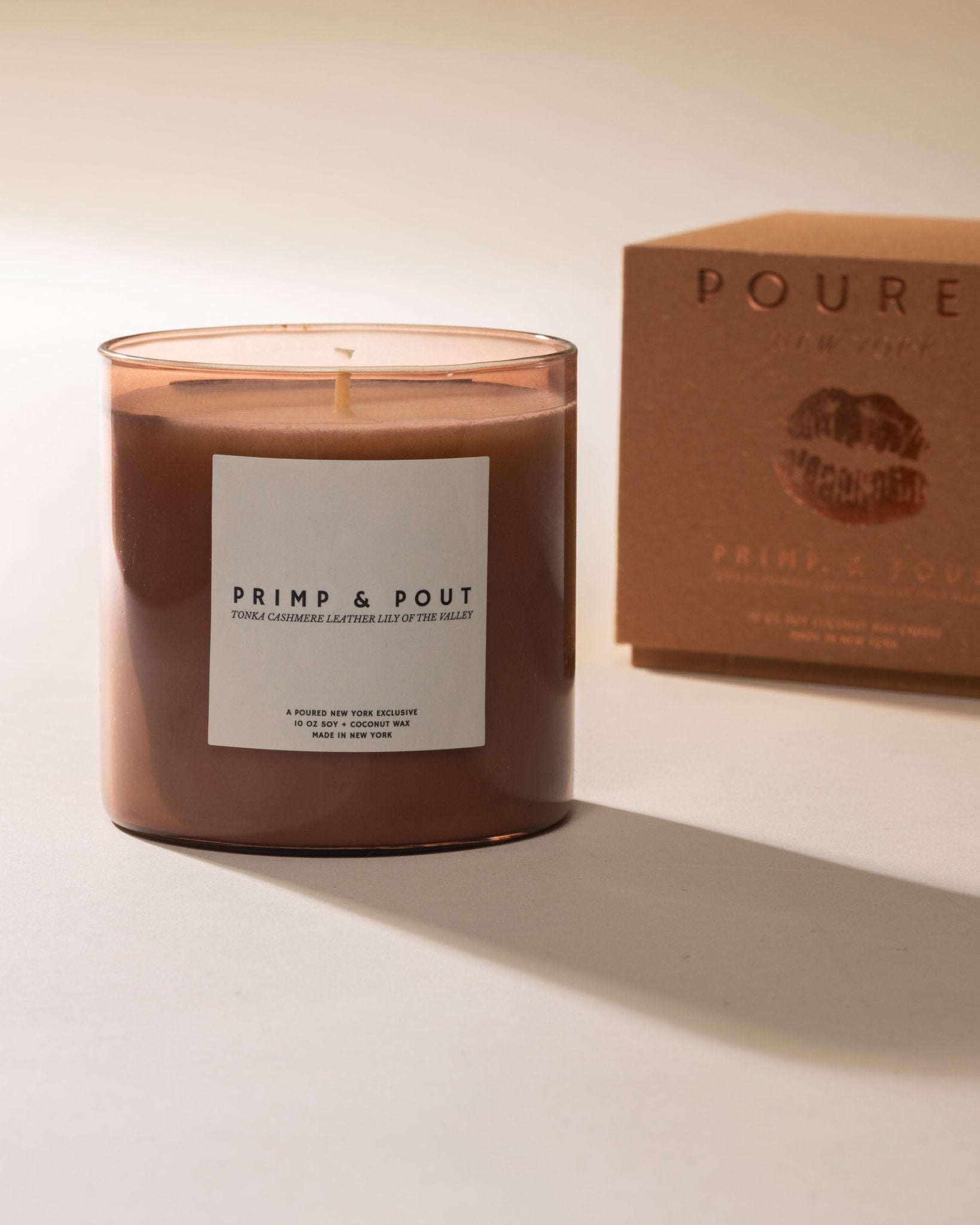Candle labeled 'Primp & Pout' with a matching box with a pouty lip decal on a neutral background