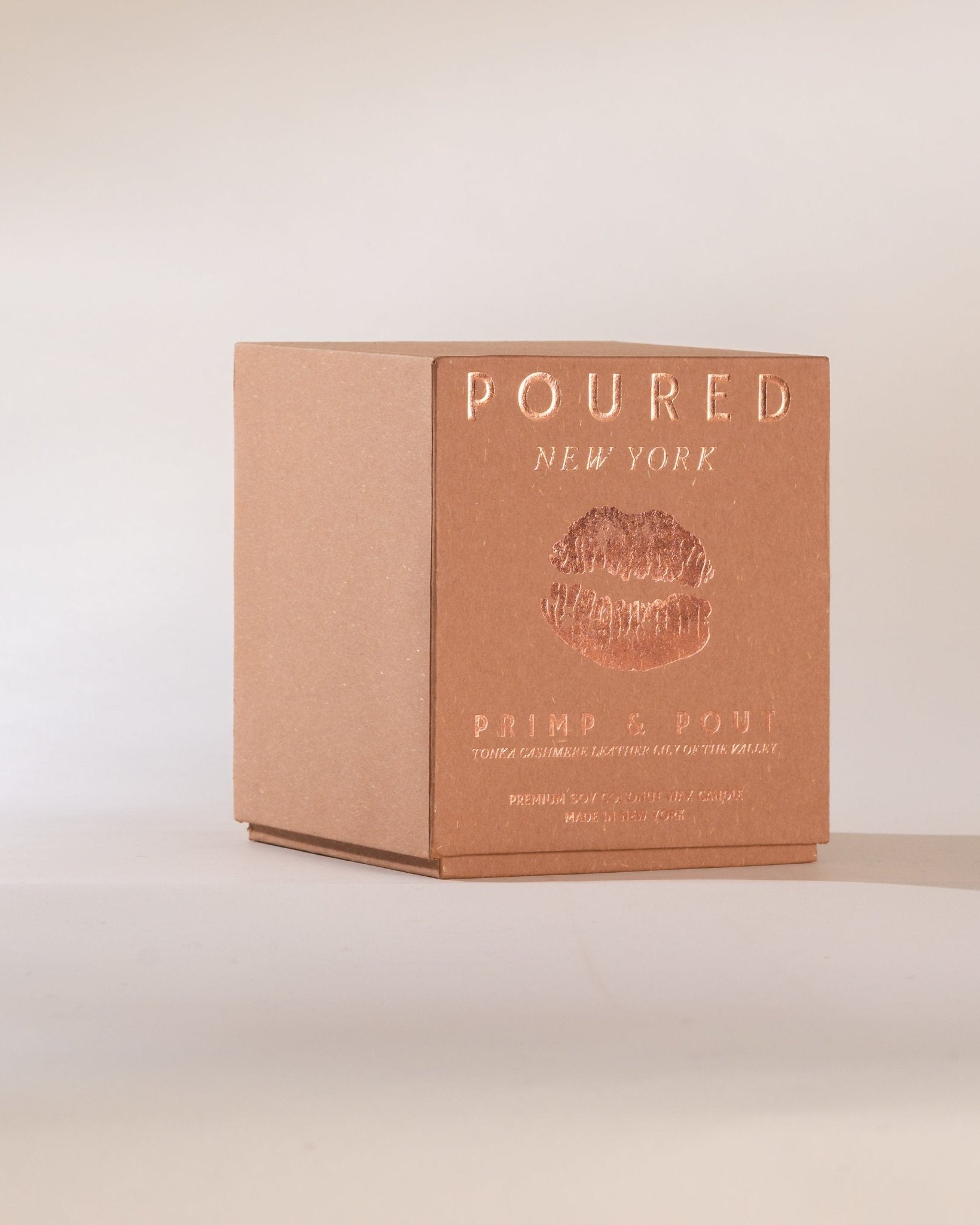 Light pinkish box with 'Poured New York' branding and a pouty lip decal on a beige background