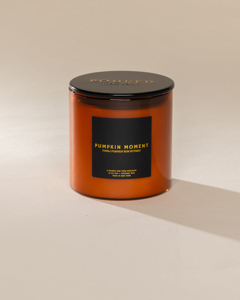 Poured New York 'Pumpkin Moment' 10 oz orange glass soy wax candle on a neutral background