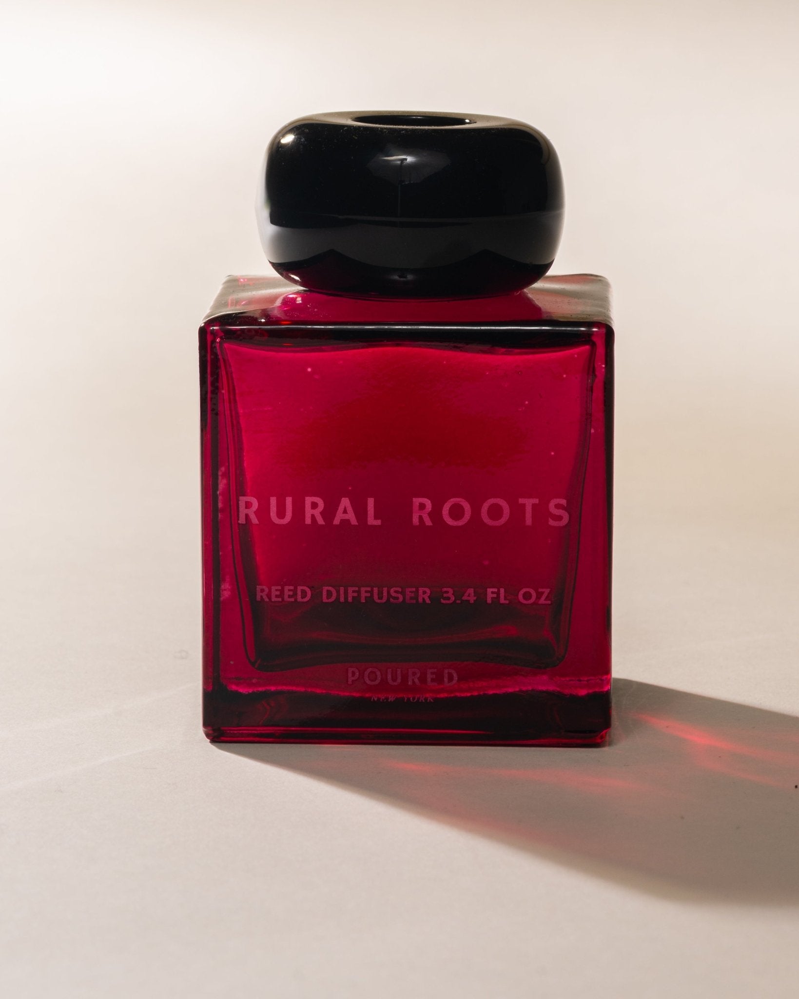 Red Rural Roots reed diffuser with black cap on a white background