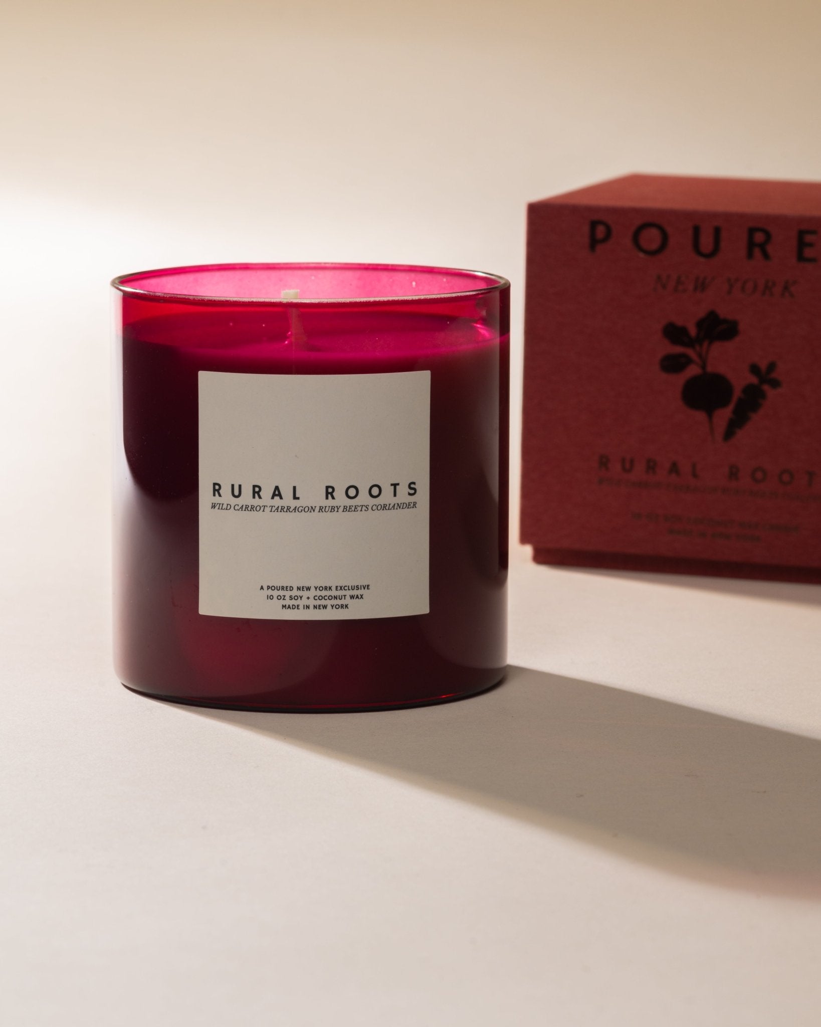 Poured New York 'Rural Roots' candle in beet red with a matching colored candle box with a beet and carrot icon on a neutral background.