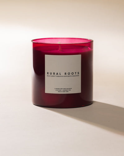 Poured New York 'Rural Roots' candle in beet red glass on a neutral background.