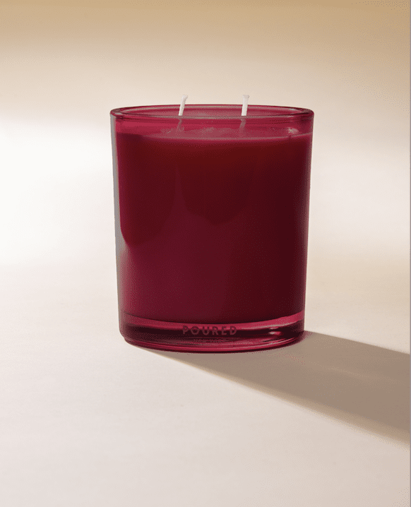 Poured New York 'Rural Roots' two wick candle in beet red glass on a neutral background.