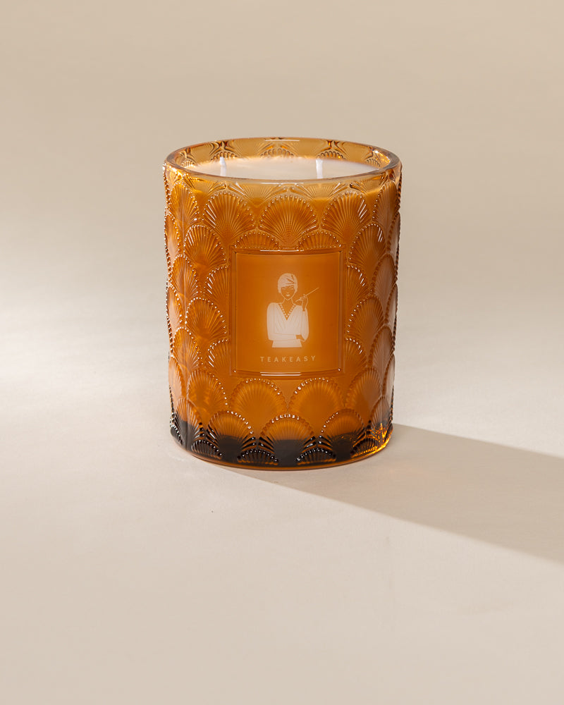Poured New York 'Teakeasy' 22 oz amber glass vintage etched double wick candle on a neutral background