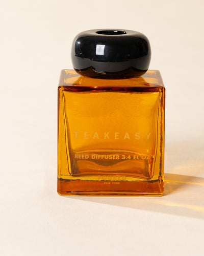 Poured New York 'Teakeasy' 3.4 fl oz reed diffuser in an amber glass vessel on a neutral background