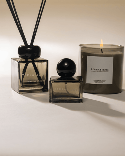 Olive green 'Terrafigue' diffuser, niche parfum, and candle lit on a neutral background