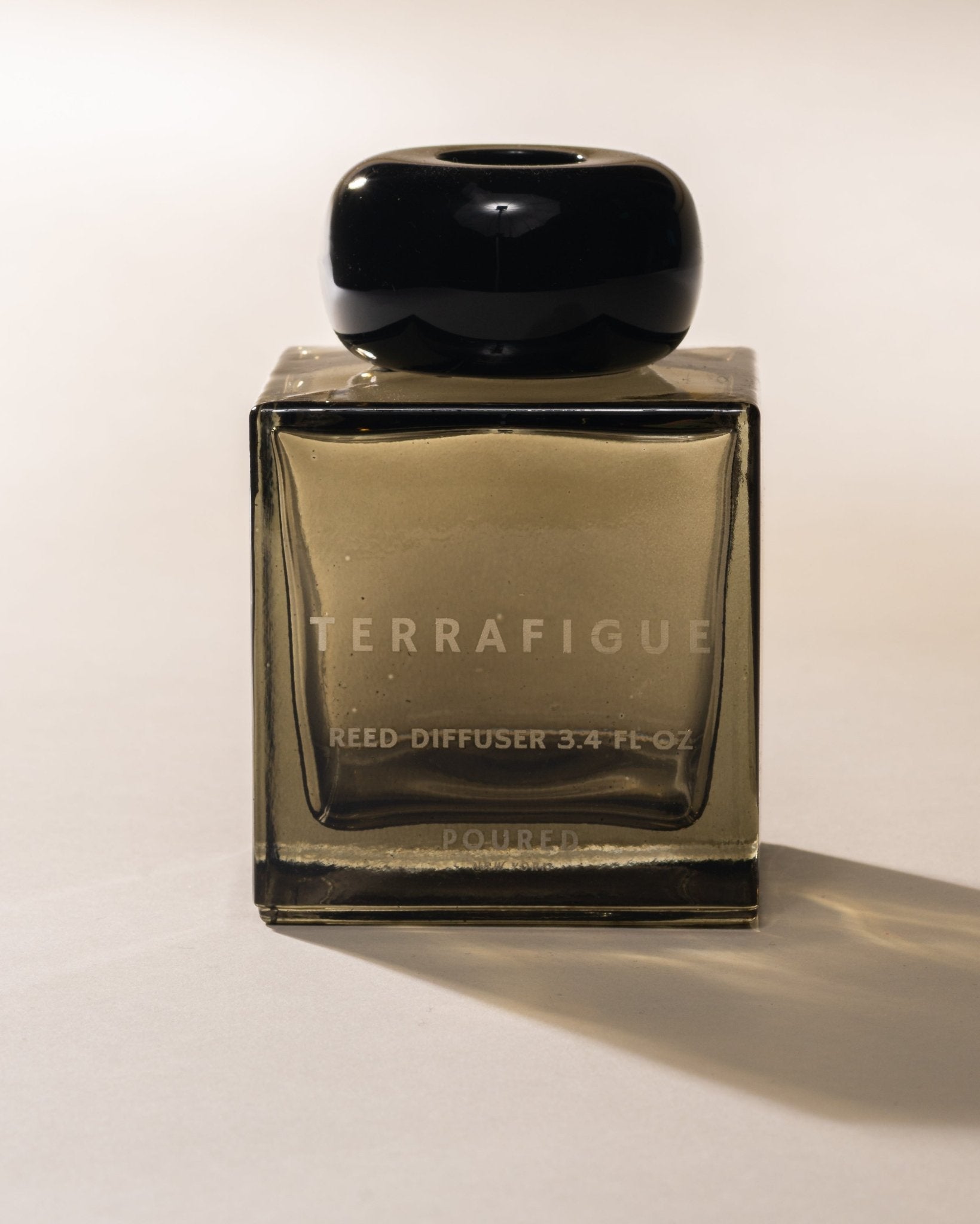 Terrafigue olive green reed diffuser bottle with black cap on a white background