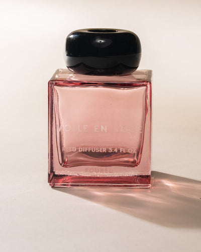 Poured New York 'Voile en Rose' pink glass reed diffuser with black cap on neutral background